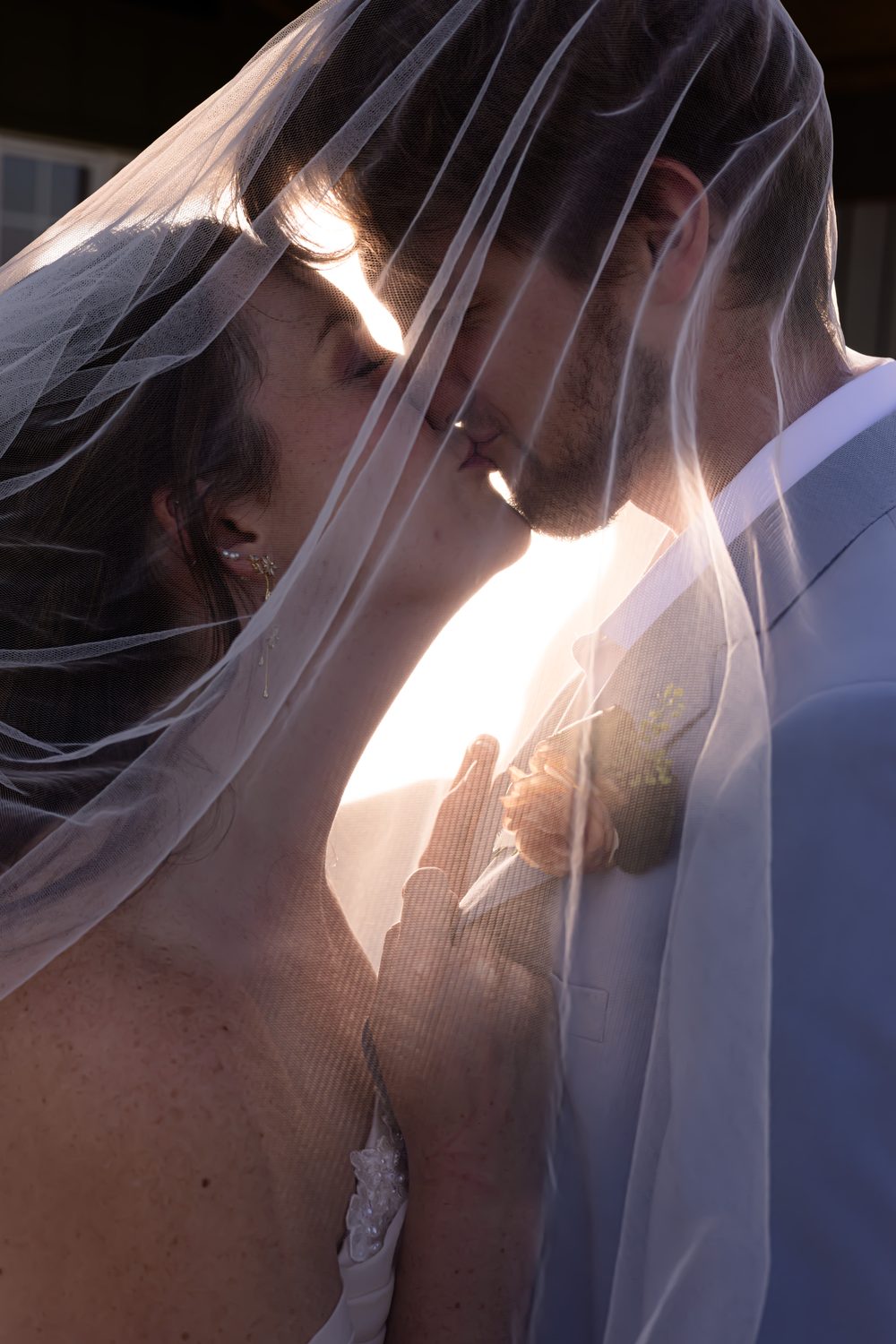 A couple kissing beneath the veil in golden evening light