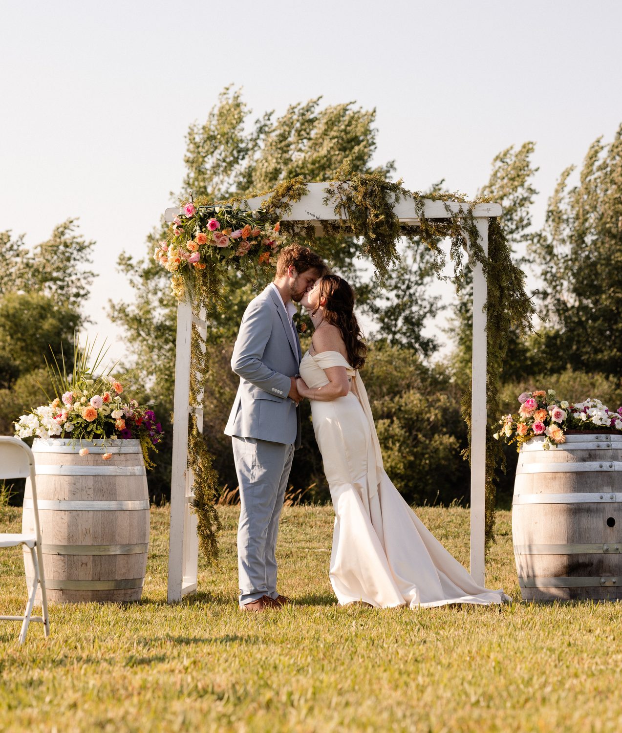 A first kiss beneath the flower-covered arbor at the vineyard's edge
